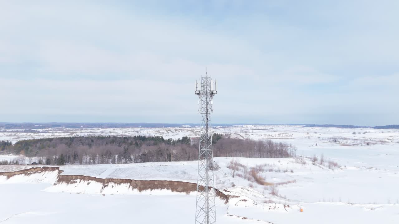 Orbita bassa di drone attorno a una torre di comunicazione in un paesaggio invernale innevato.