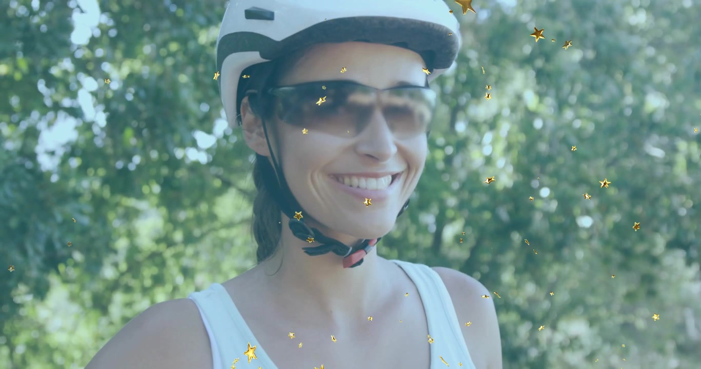 Ciclista donna che riceve una panoramica in movimento e sorride nella foresta con stelle alla deriva, celebrando la forma fisica.