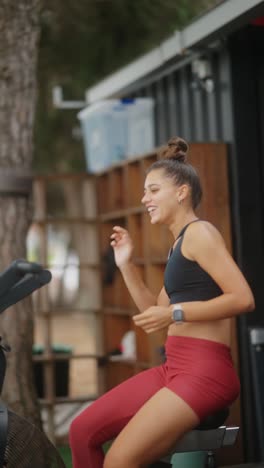 young woman smiling and exercising on an outdoor stationary bike