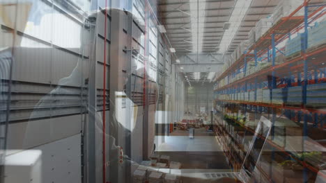 animation of caucasian man using laptop over warehouse