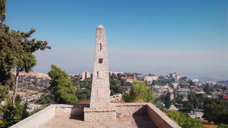stone monument on a hilltop overlooking a cityscape