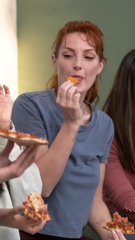Diverse friends cheering up for woman bringing pizzas during weekend party at home