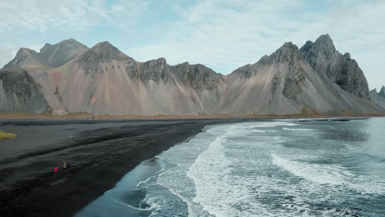 viajeros en la playa de stokksnes, vista épica de la montaña irregular de vestrahorn