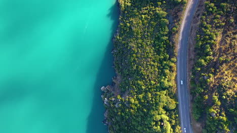 top down aerial view of a scenic highway along a picturesque mountain lake in new zealand