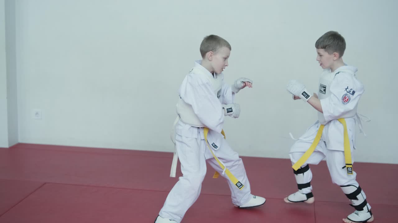Young martial artists in white gi and yellow belts practicing kudo techniques with focus and determination