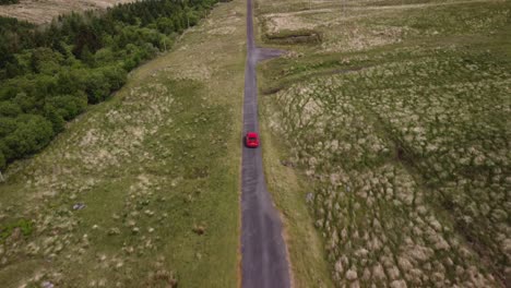 Vehículo-Rojo-Rastreado-Desde-Lo-Alto-Por-Un-Dron-A-Lo-Largo-De-Una-Carretera-De-Vía-única