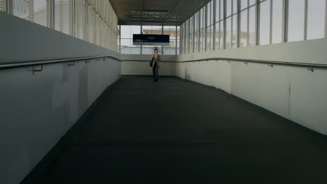 Person Walking Through Modern Train Station Overpass