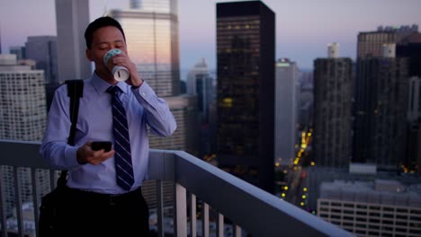 asian manager using smartphone on rooftop at sunrise