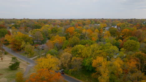 Aerial-over-Kirkwood-neighborhood-and-towards-train-tracks-running-through-trees-and-houses-in-Autumn-at-peak-color