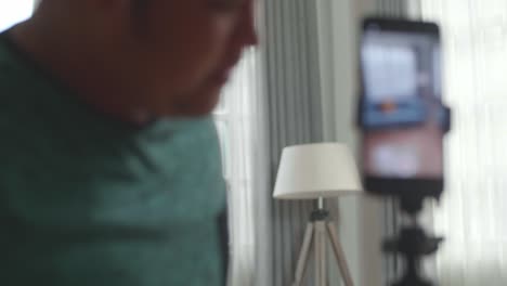 asian man blogger shoots video content for social networks by smartphone camera, magician with playing cards