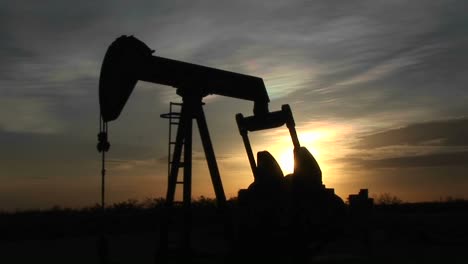 medium shot of a silhouetted oil pump turning in the new mexico desert 1