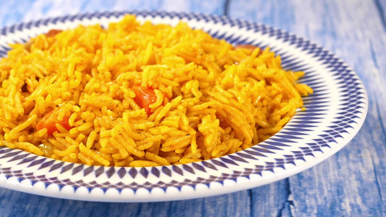 Primer plano de delicioso arroz pilaf amarillo sobre una mesa de madera azul