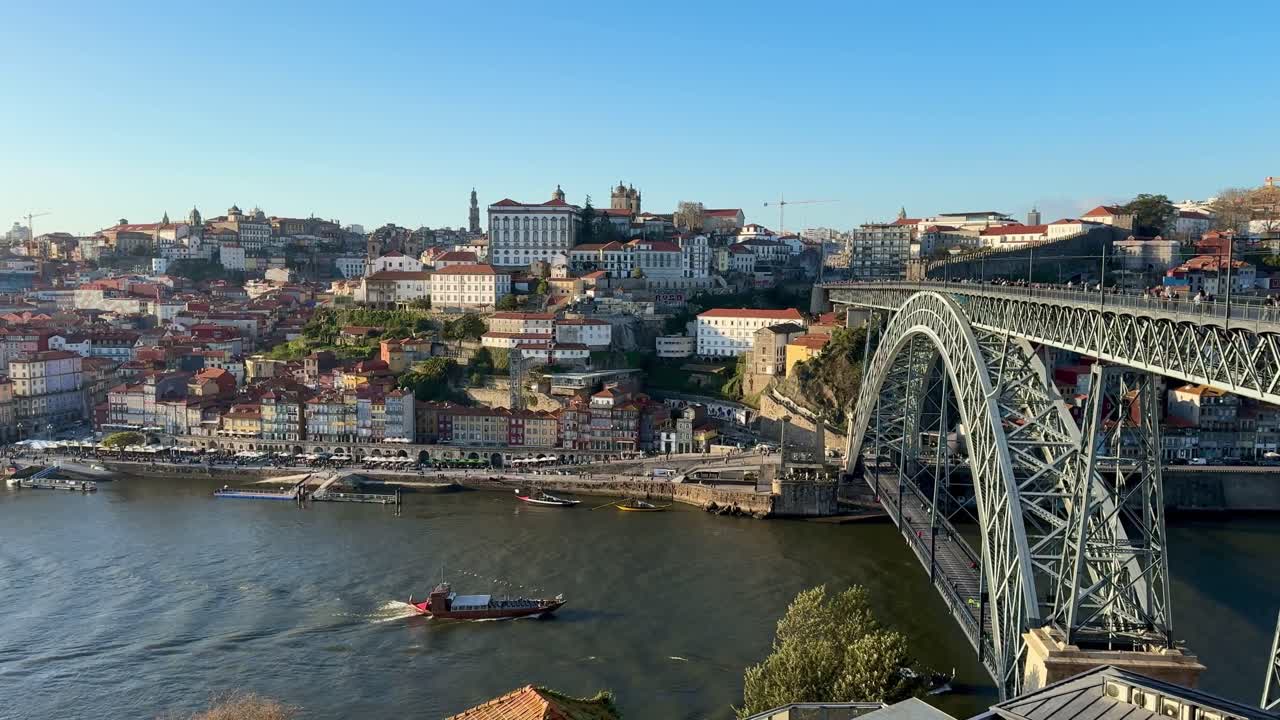 Slow motion view of Porto, Portugal, showcasing the Dom Luís I Bridge, Douro River, colorful buildings, and historic cityscape under sunlight.