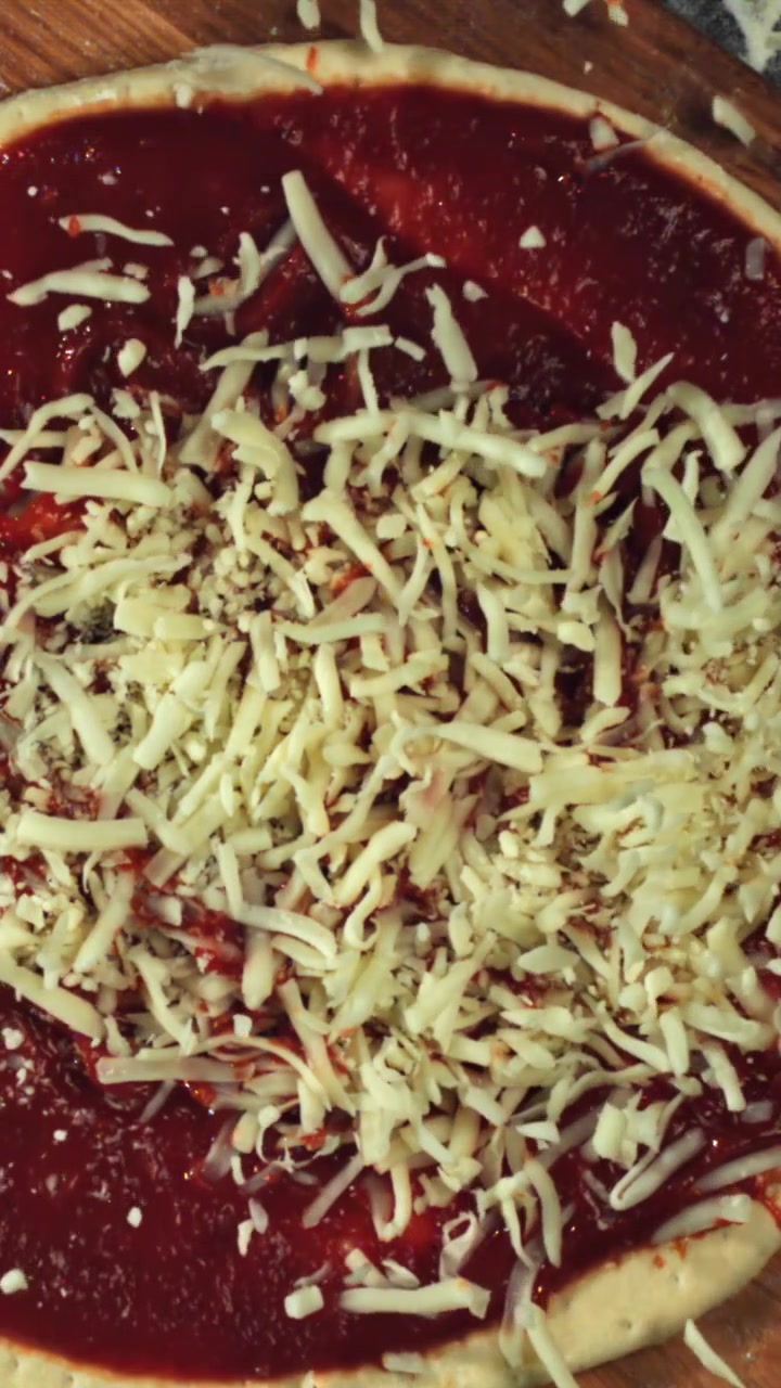Aggiunta di mozzarella sfilacciata su una pizza