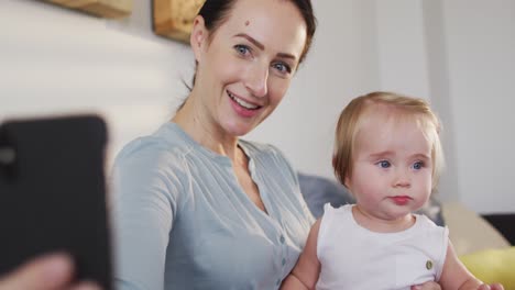 madre caucásica tomando una selfie con su bebé en el teléfono inteligente en casa