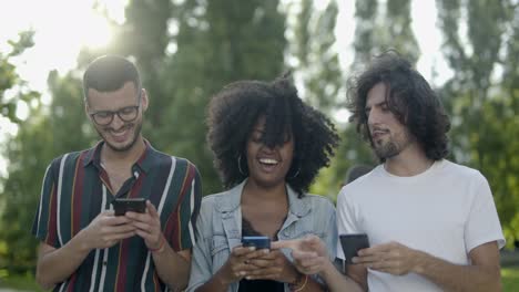 relaxed friends talking and using smartphones during stroll