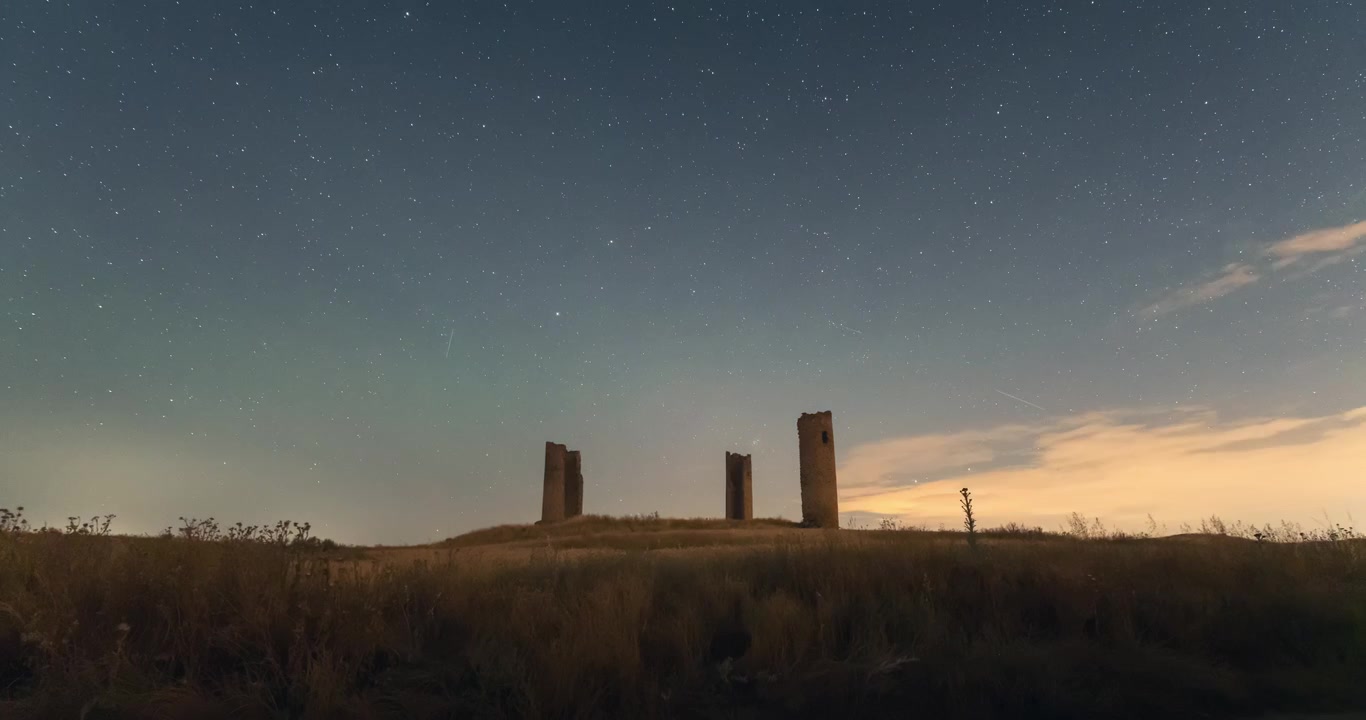 Campo di grano giallo, raccolto di cereali e torri del Castello di Galvez durante un timelapse notturno del cielo stellato