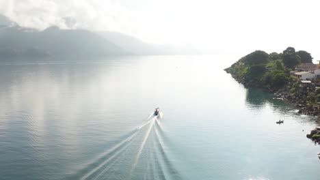 An-Einem-Nebligen,-Mystischen-Tag-Fährt-Ein-Ausflugsboot,-Das-Große-Kielwasserwellen-über-Den-Atitlan-See-In-Guatemala-Hinterlässt