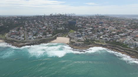 cityscape in tamarama beach with splashing waves from mackenzies bay - eastern suburbs, sydney, new south wales, australia