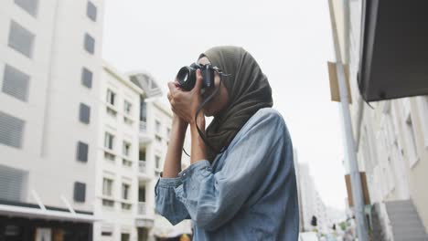 woman wearing hijab taking photo in the street