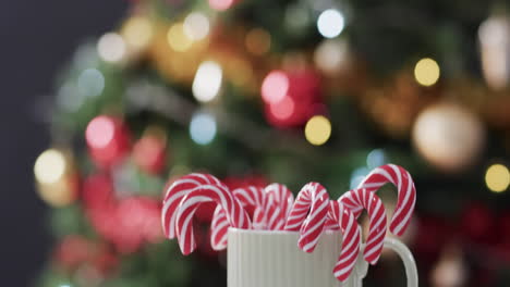 Video-of-white-mug-with-christmas-cnady-canes-and-christmas-tree-lights-with-copy-space