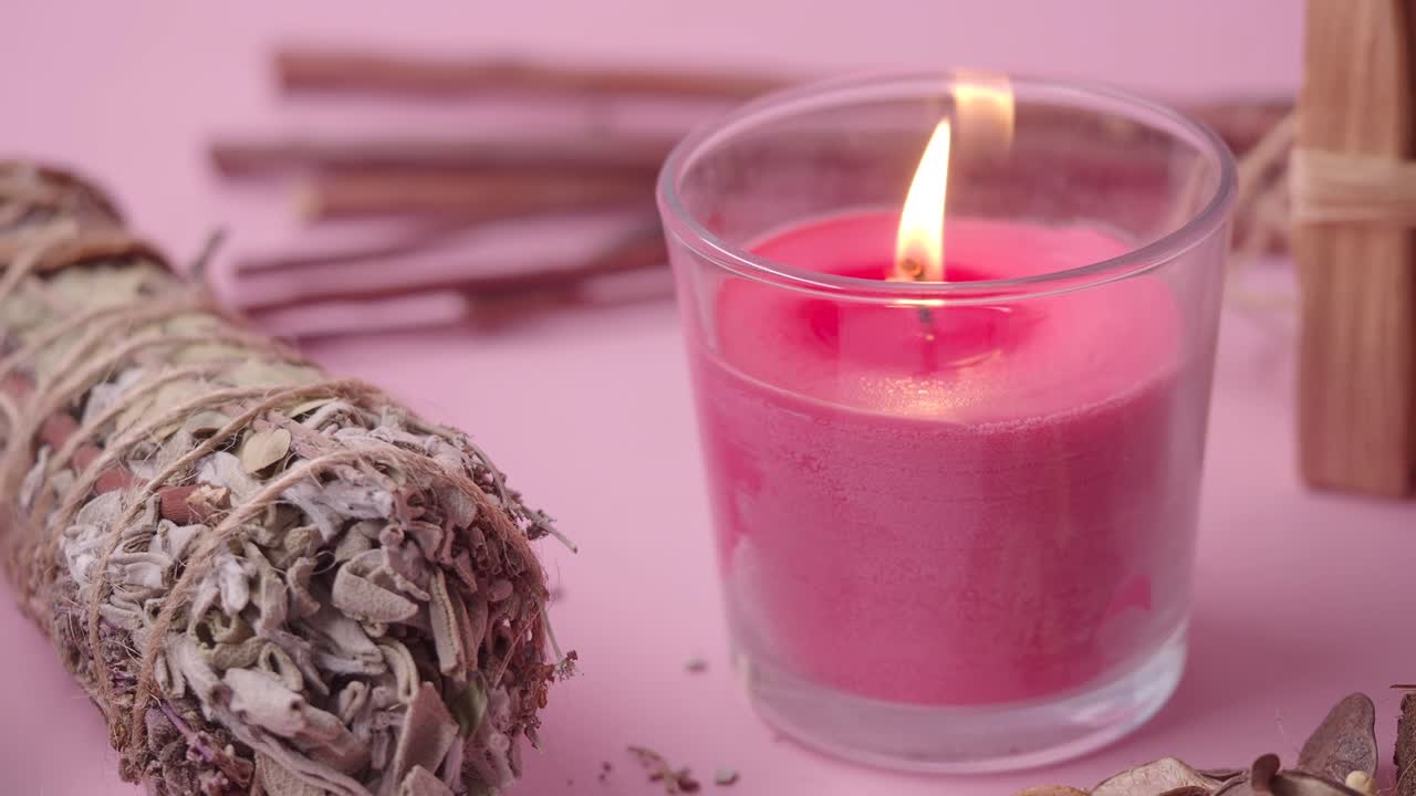 Adaçayı tütsü çubuğu ve Palo Santo ile yanan pembe mum.