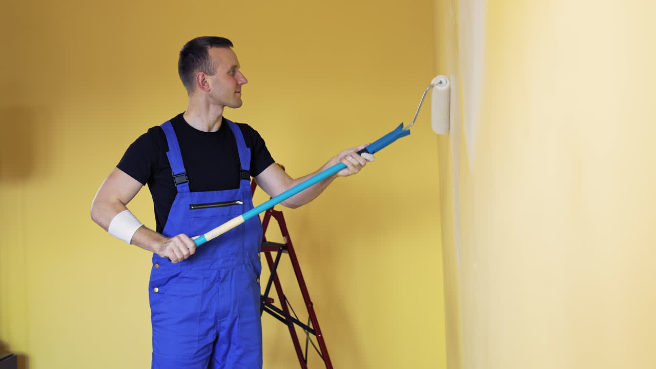 Man Decorating Room In New Home. Man painting wall during home decoration with roller brush