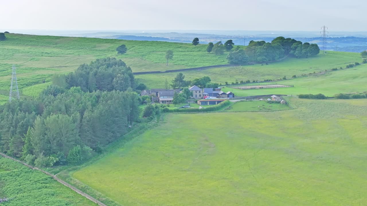 A serene countryside landscape with green fields and a cluster of houses nestled among trees. The peaceful rural setting evokes tranquillity and showcases the simplicity of countryside living
