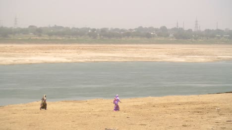 two women walking along riverbank in varanasi