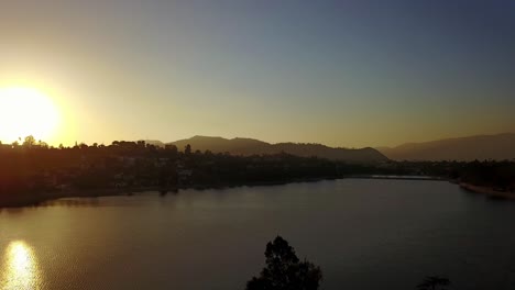 Aerial-descending-and-panning-shot-of-urban-lake-in-Los-Angeles-during-sunset