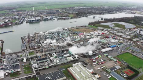 städtisches industriegebiet am flussufer mit fabrikschornsteinrauch, stadion und straßen