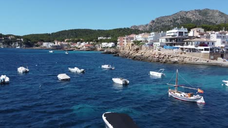 drone flying slowly at lower altitude over blue ocean and boats in the natural harbor in mallorca spain on a sunny and windy day