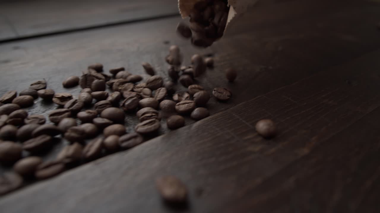 Dark Roasted Coffee Beans Spilling Out of Paper Bag on Wooden Table