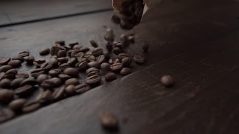 dark roasted coffee beans spilling out of paper bag on wooden table