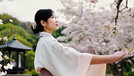 a woman in a traditional japanese kimono smiles happily as she stands in a garden filled with beautiful cherry blossoms