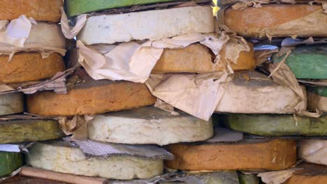 a stack of round cheese rounds for sale at a market