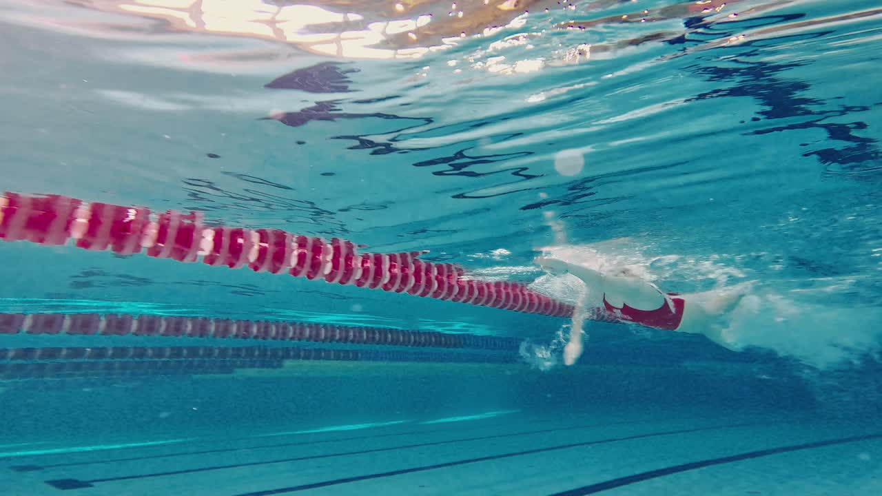 mujer nadando bajo el agua en una piscina