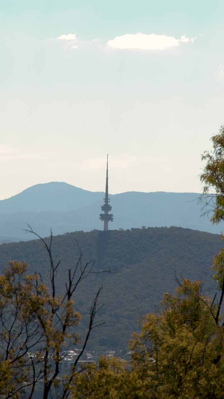 Una lenta panoramica rivela una torre di comunicazione distante in cima a una cresta montuosa boscosa