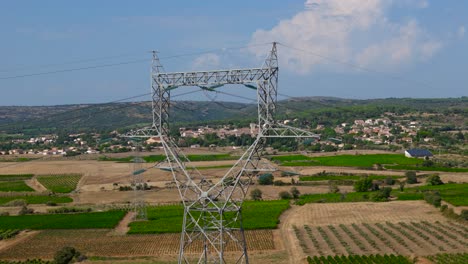 slow establishing shot of a large electricity pylon in the middle of a vineyard