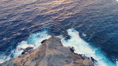 vista aérea de las olas del océano rompiendo en una montaña rocosa