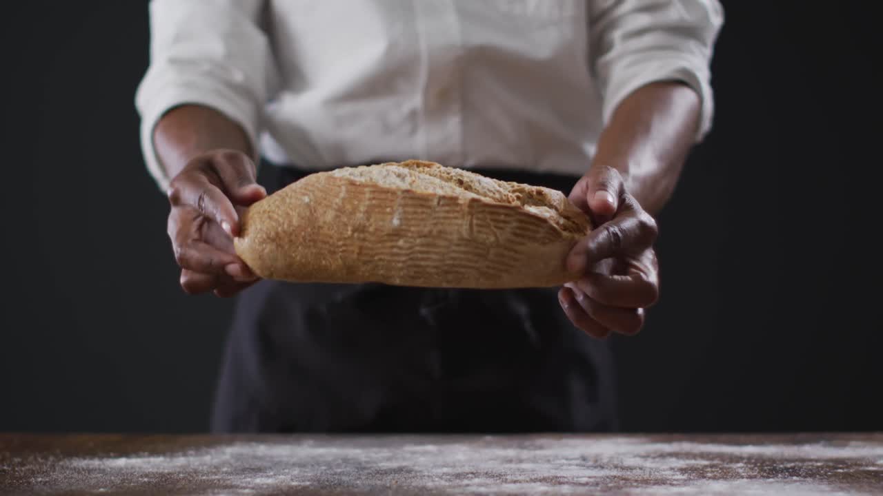 Video of cook holding loaf of bread on black background