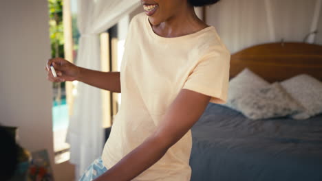 Close-Up-Of-Excited-Couple-In-Bedroom-At-Home-Celebrating-Positive-Pregnancy-Test-Result