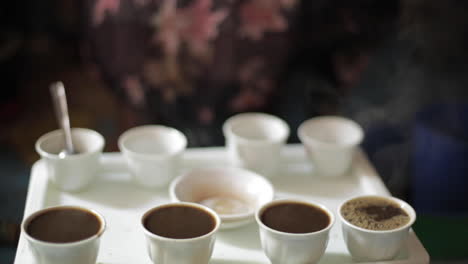 African-Woman-Pours-Cups-of-Coffee-From-Kettle-on-Tray,-Close-Up