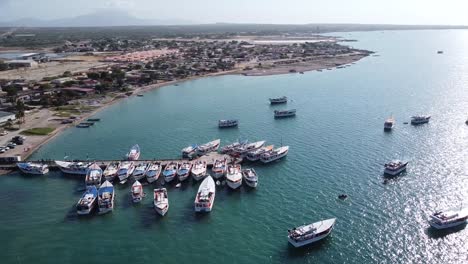 rising drone shot of boats at port loading fuel and selling fish after catch