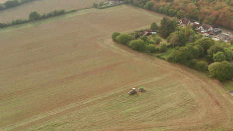 wide circling aerial shot of a tractor ploughing a large field