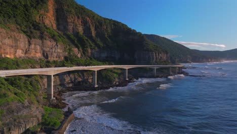 sunrise sea cliff bridge costal drone view iconic famous stanwell park cars driving waves south coast nsw australia landscape royal national park wollongong coalcliff iiawarra sydney down jib