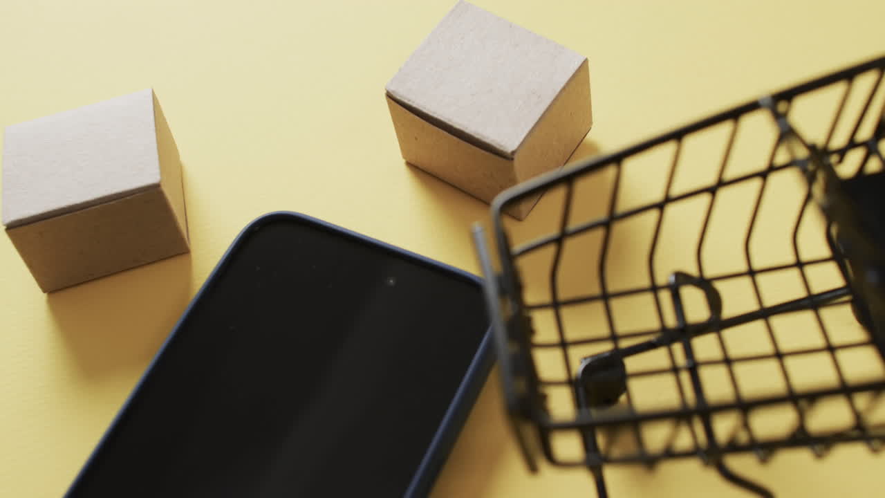 video de un teléfono inteligente con pantalla en blanco, cajas, carrito de compras sobre fondo amarillo