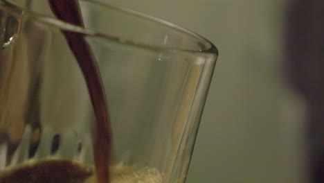 Frothy-draft-beer-is-poured-into-glass-in-close-up-view,-bar-interior