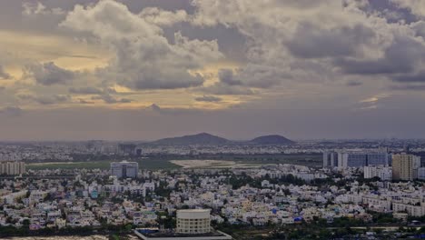 moving aerial shot of urban cityscape with cumulus clouds in sky and a faint glow at horizon.