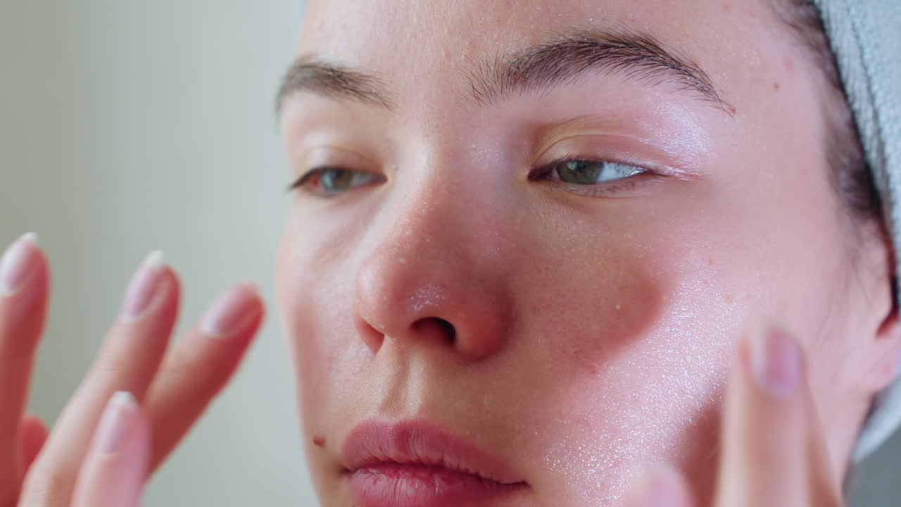 Close-up of woman massaging her cheeks with hands, applying skincare for a smooth, glowing complexion, focus on beauty routine emphasizing soft touch and moisturizing for healthy skin